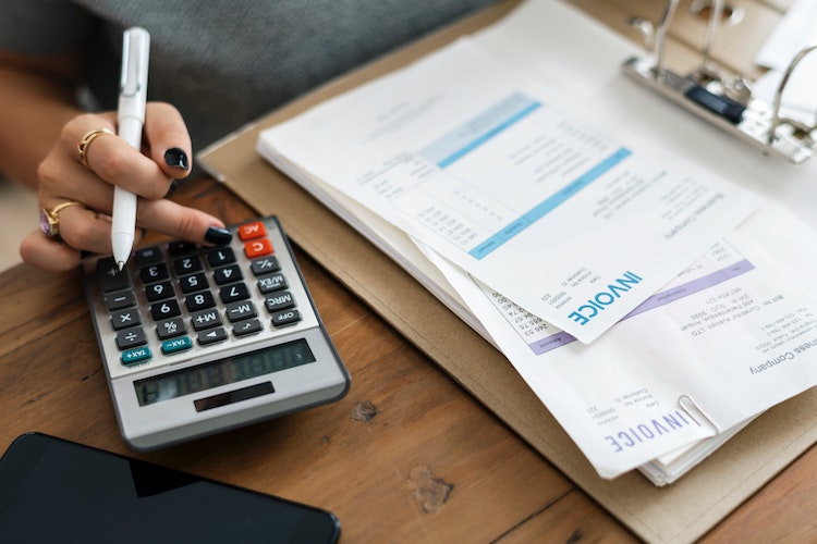 Invoices on a table alongside a calculator.